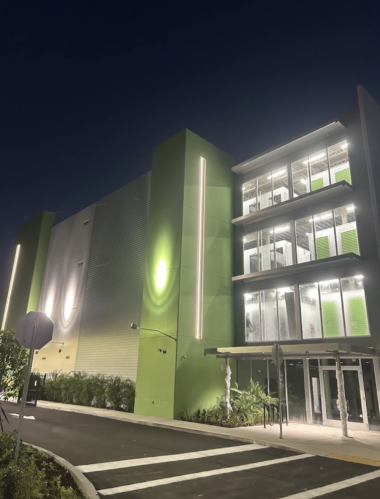 Illuminated white and green storage building at night